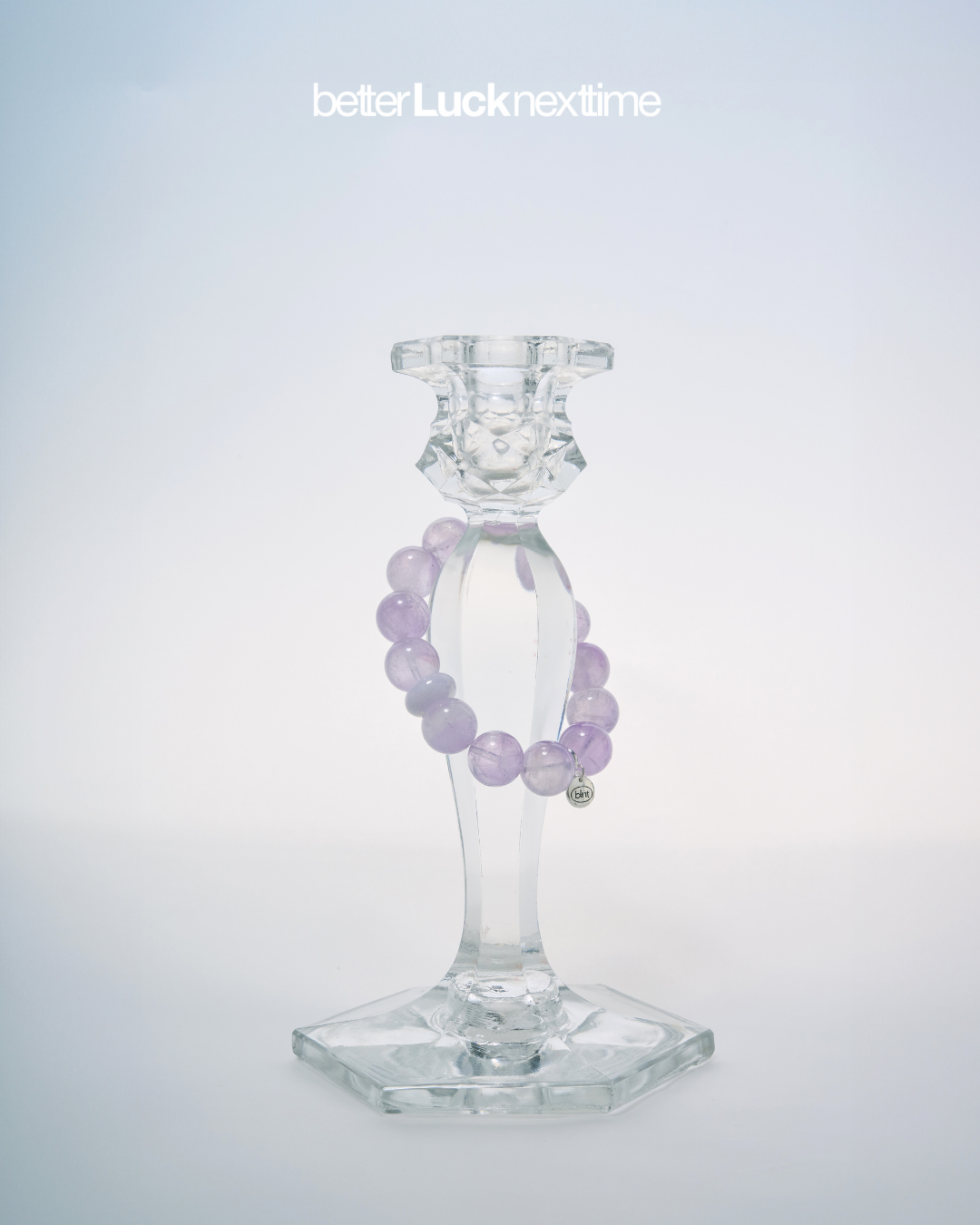 Better Luck Next Time "The Oracle" bracelet, purple crystal beads with jade accent piece, displayed in styled setting on About page.